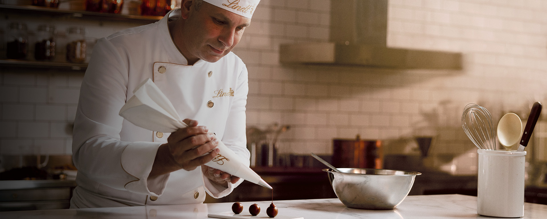 A maître chocolatier is filling LINDOR truffles with a piping bag (Photo)