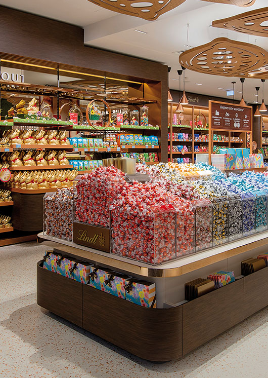 A Lindt store with shelfs and containers for different Lindt products, such as LINDOR truffles and Lindt gold bunnies (Photo)