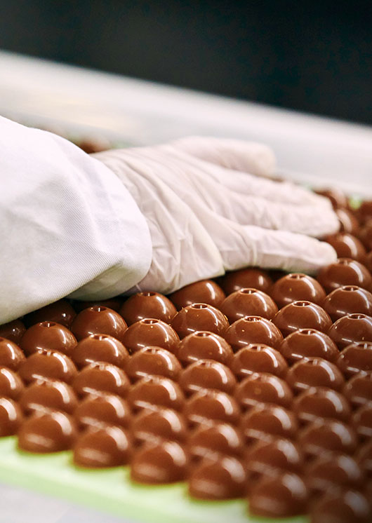 LINDOR truffles during the cooling process checked by an employee in hygienic gloves (Photo)