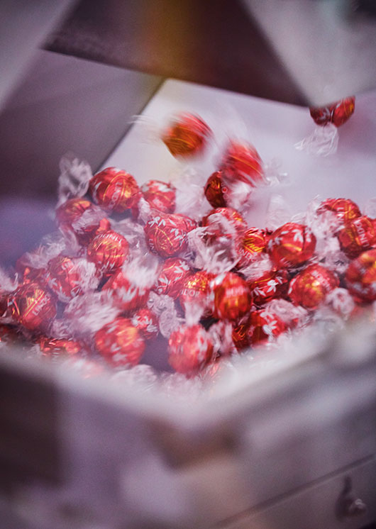 Red LINDOR truffles wrapped by the wrapping machine (Photo)