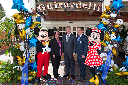 Ernst Tanner und zwei weitere Personen und Micky Mouse und Minnie Mouse vor einem Ghirardelli Schild (Foto)