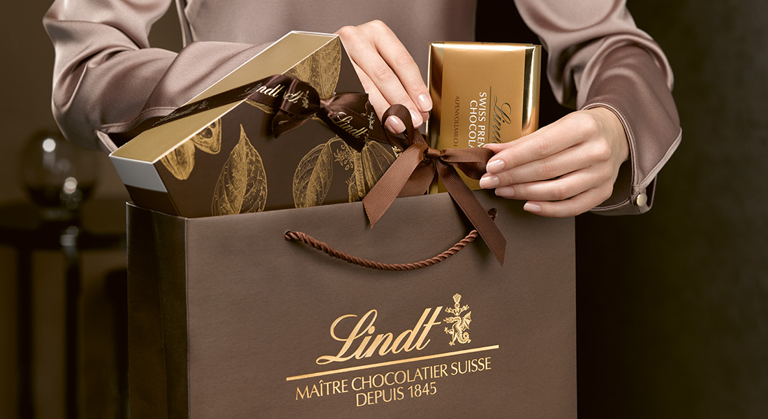 Lindt Schokolade in einer Geschenktüte. Farbig abgestimmt in braun und gold. (Foto)