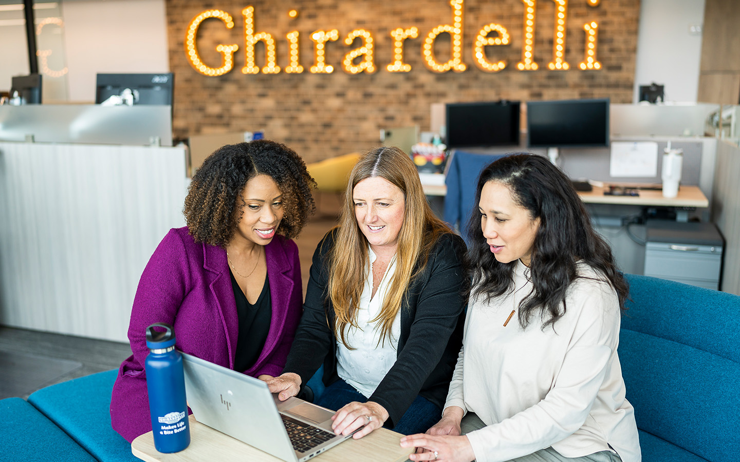 Three employees sitting around a computer at Ghirardelli (Photo)